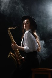 Photo of Professional musician playing saxophone on dark background with smoke