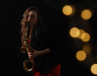 Photo of Professional musician playing saxophone on black background with blurred lights. Bokeh effect