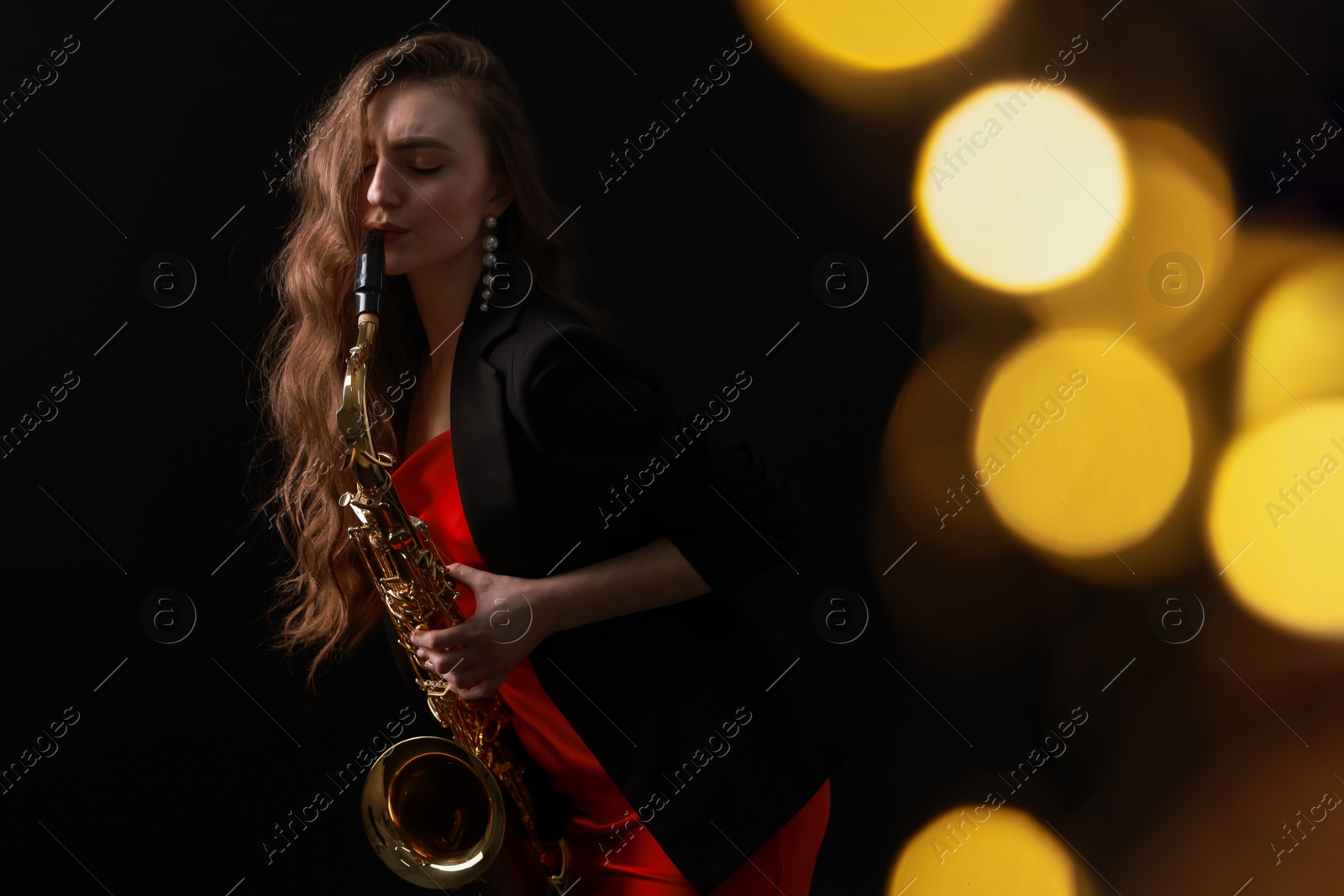 Photo of Professional musician playing saxophone on black background with blurred lights. Bokeh effect