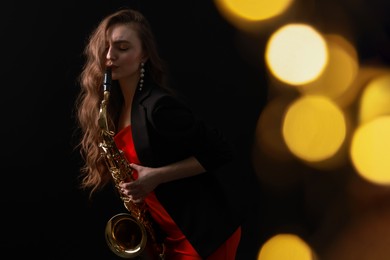 Professional musician playing saxophone on black background with blurred lights. Bokeh effect