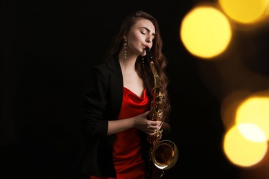 Photo of Professional musician playing saxophone on black background with blurred lights. Bokeh effect