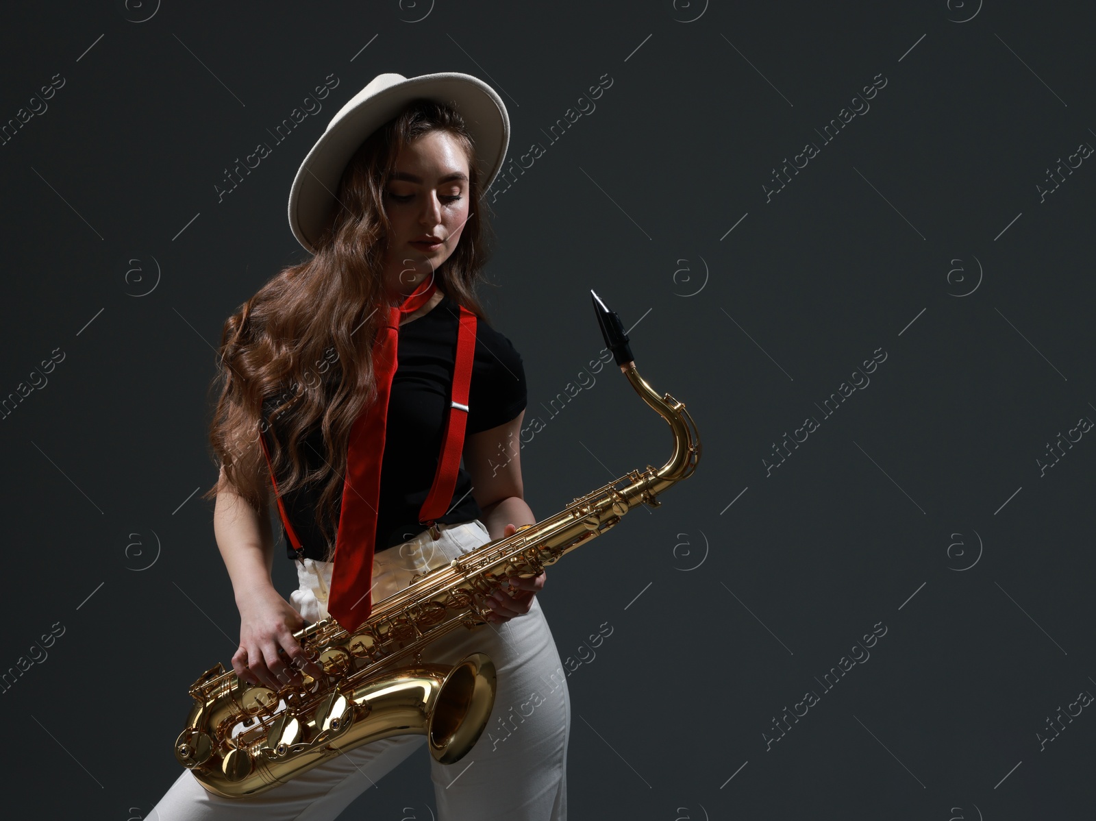 Photo of Professional musician with saxophone on grey background. Space for text