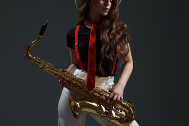 Photo of Professional musician with saxophone on grey background, closeup