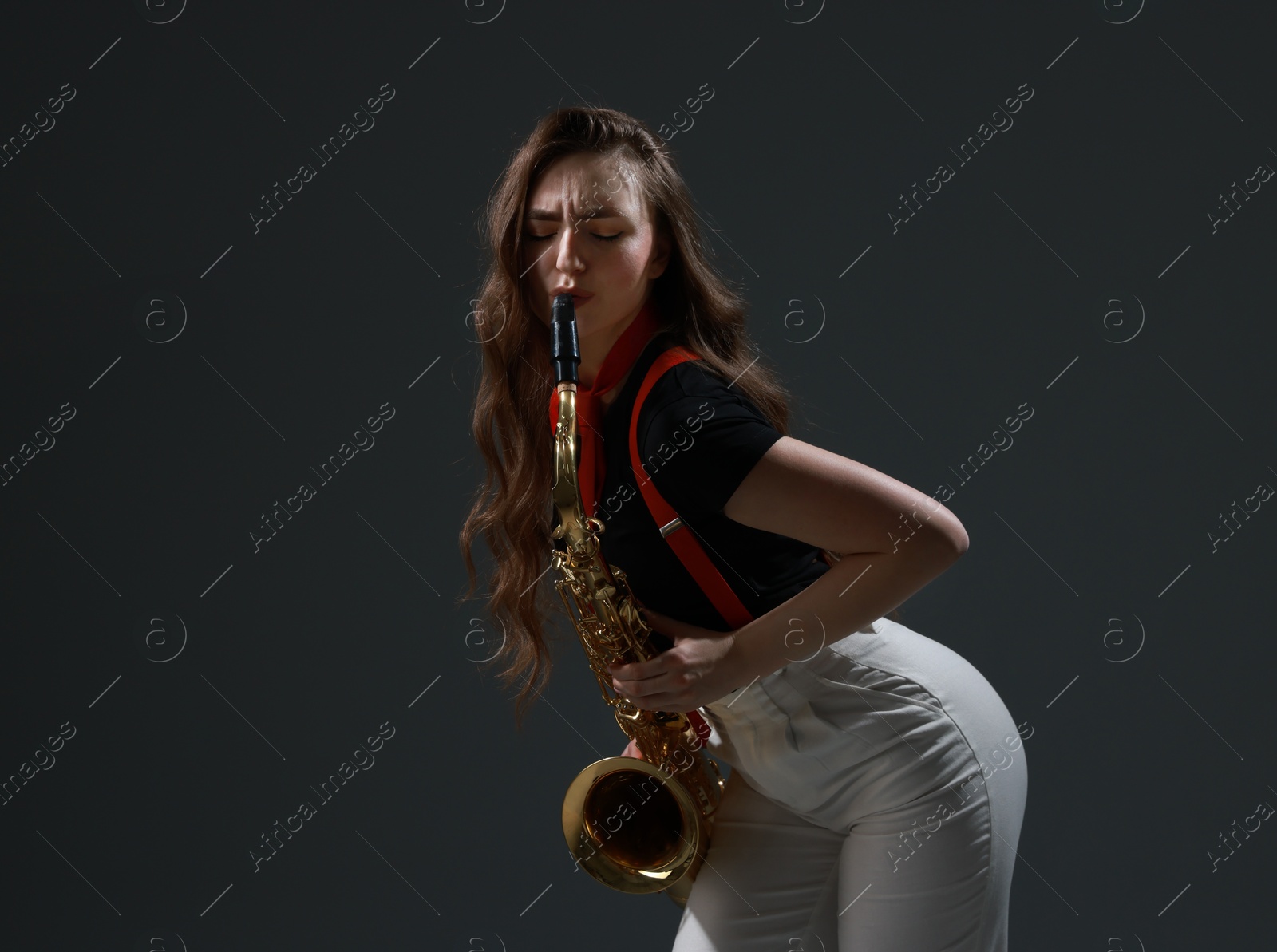 Photo of Professional musician playing saxophone on grey background. Space for text