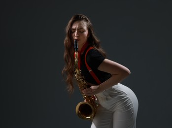 Photo of Professional musician playing saxophone on grey background. Space for text