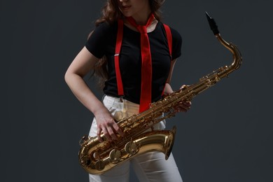 Photo of Professional musician with saxophone on grey background, closeup