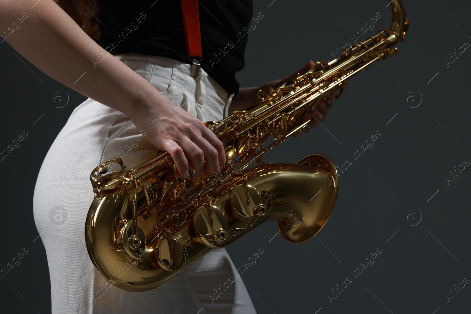 Photo of Professional musician with saxophone on grey background, closeup