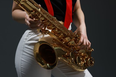 Photo of Professional musician with saxophone on grey background, closeup