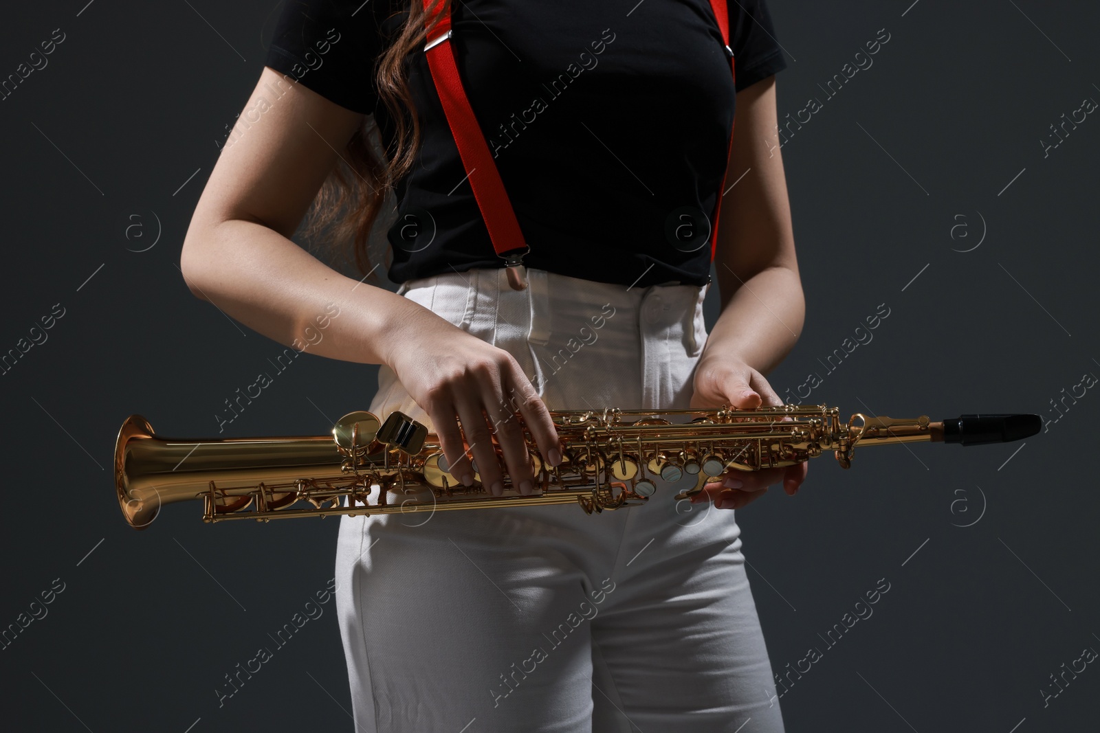 Photo of Musician with soprano saxophone on grey background, closeup