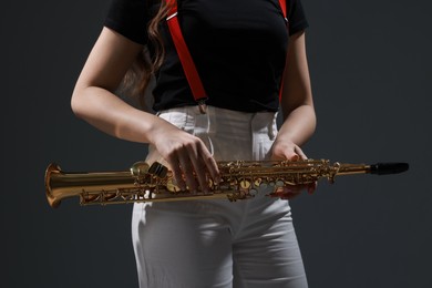 Photo of Musician with soprano saxophone on grey background, closeup