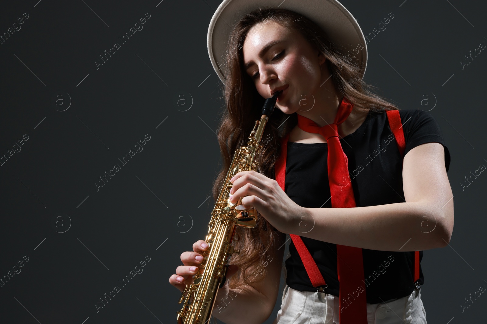 Photo of Musician playing soprano saxophone on grey background. Space for text