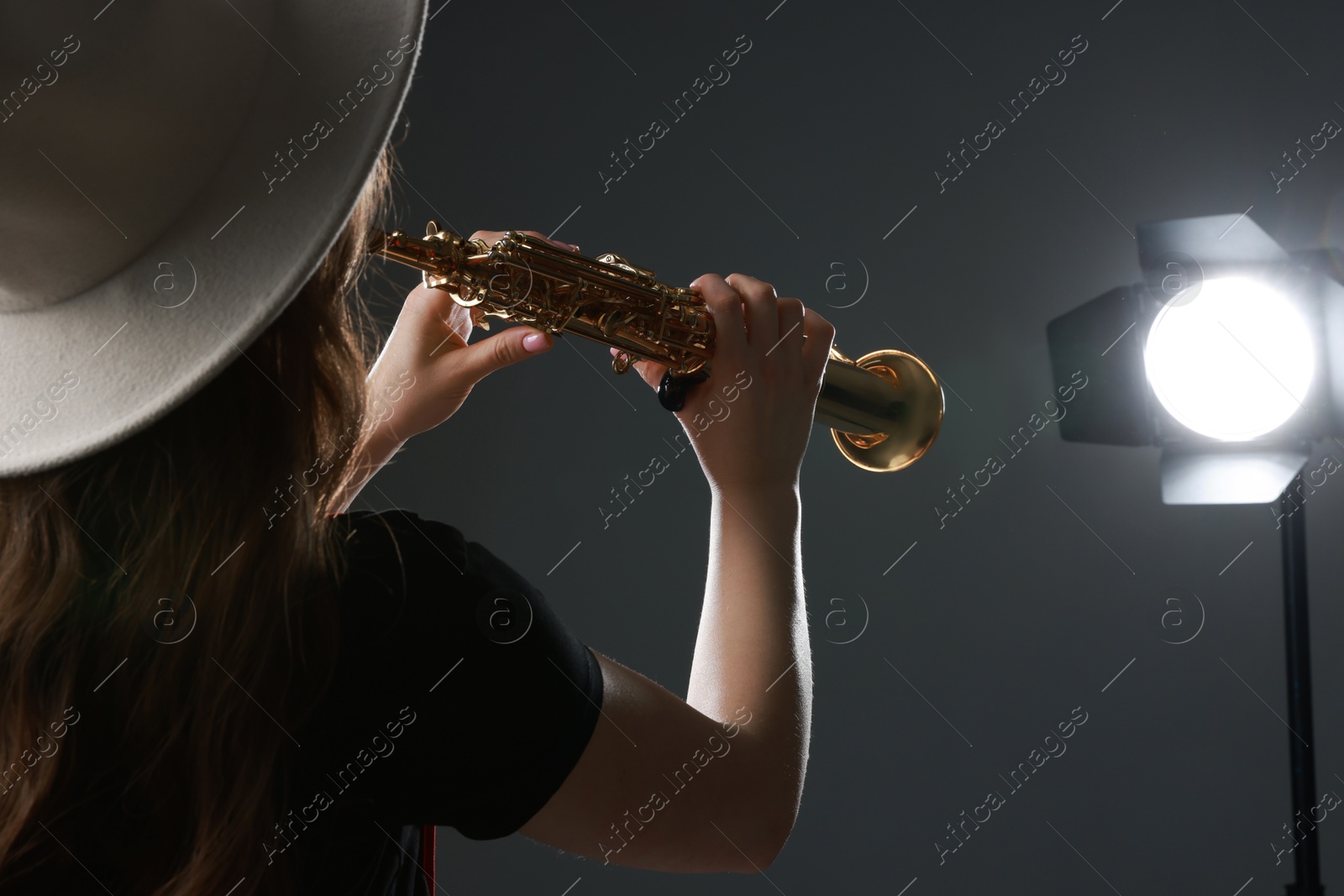 Photo of Musician playing soprano saxophone on grey background, closeup