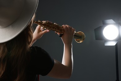 Musician playing soprano saxophone on grey background, closeup