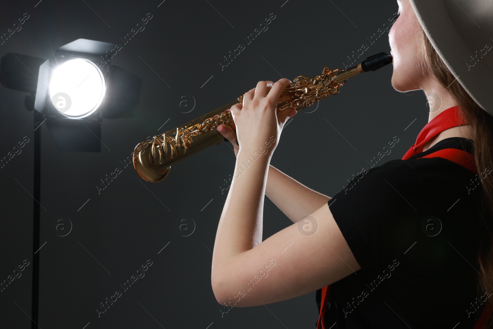 Photo of Musician playing soprano saxophone on grey background, closeup