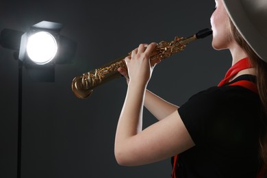 Photo of Musician playing soprano saxophone on grey background, closeup