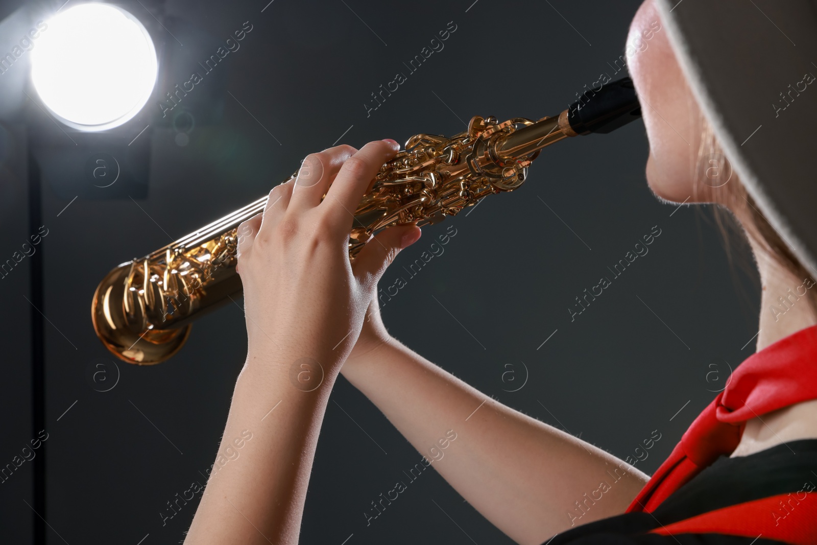 Photo of Musician playing soprano saxophone on grey background, closeup