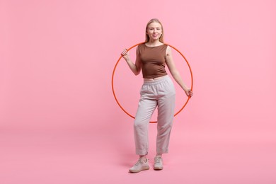 Photo of Beautiful young woman with hula hoop on pink background