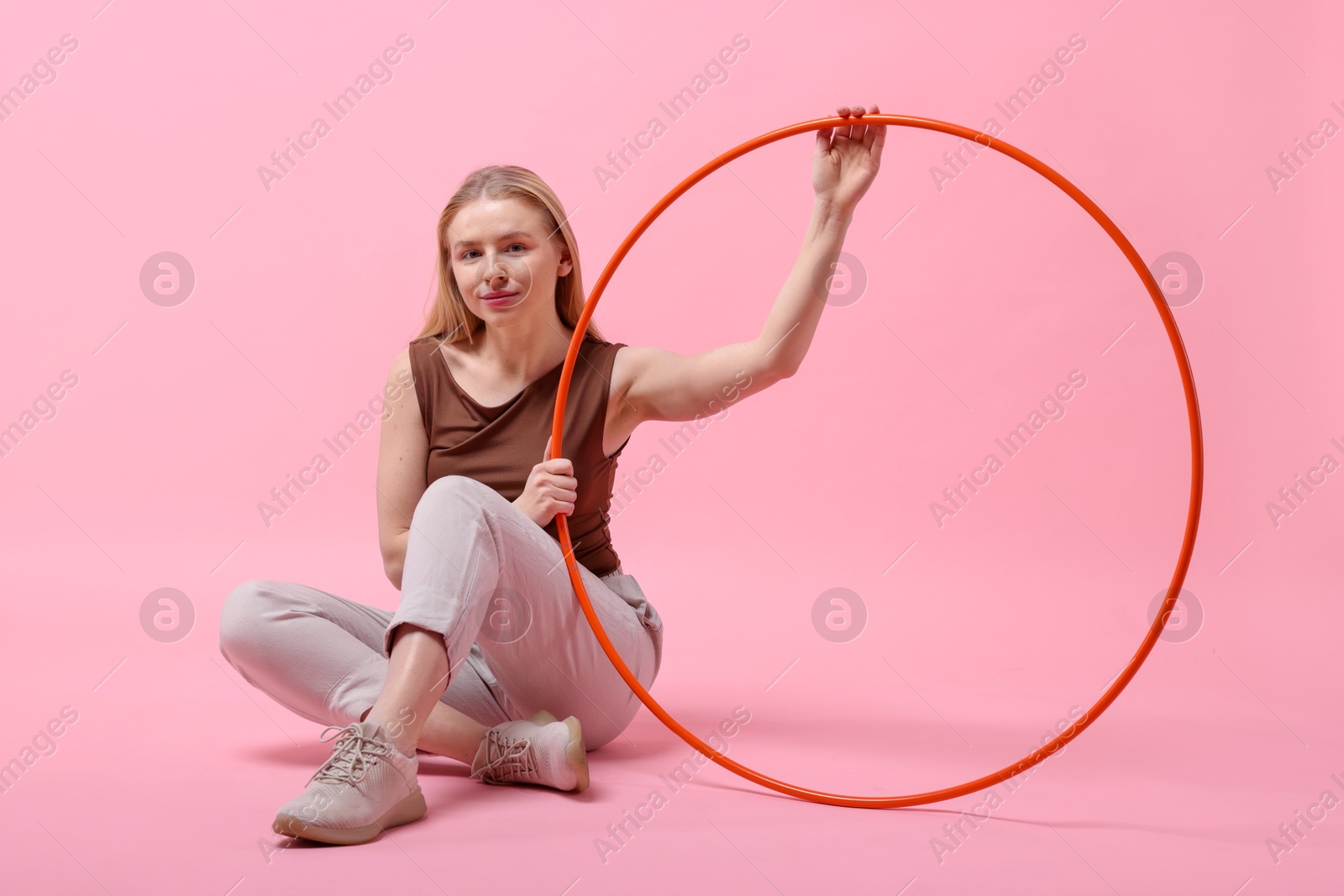 Photo of Beautiful young woman with hula hoop on pink background