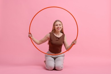 Photo of Beautiful young woman with hula hoop on pink background