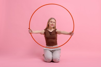 Photo of Beautiful young woman with hula hoop on pink background