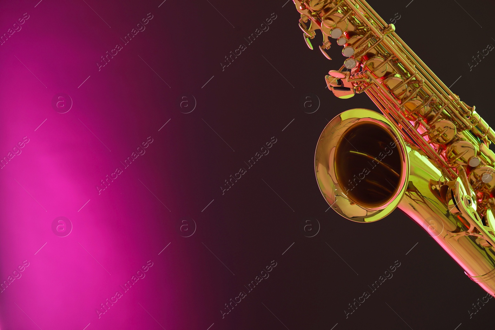 Photo of Golden saxophone on color background, closeup. Space for text