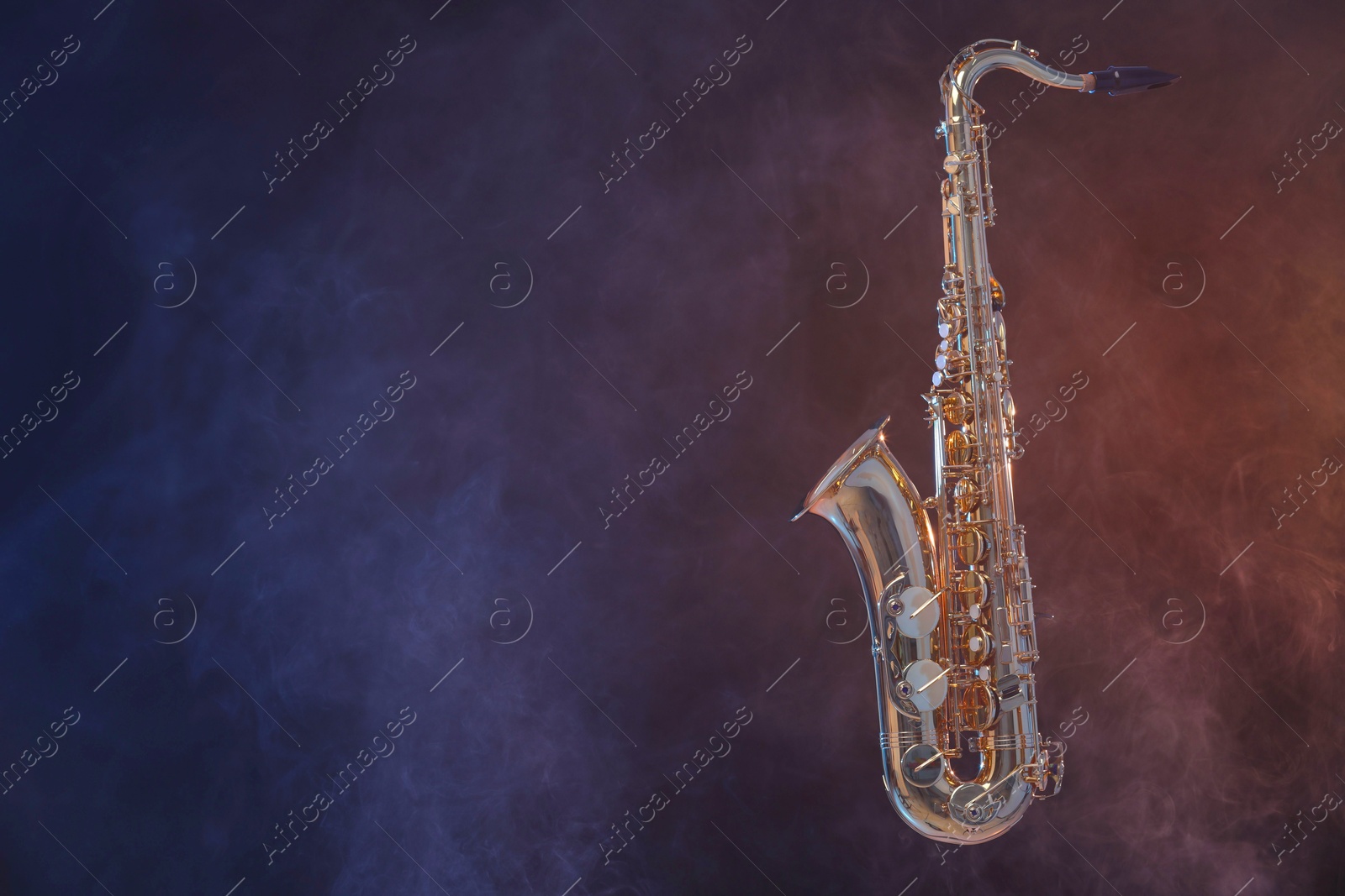 Photo of Golden saxophone on dark background with smoke. Space for text