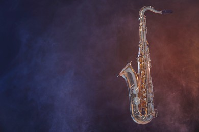 Photo of Golden saxophone on dark background with smoke. Space for text