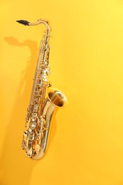 Photo of Golden saxophone on yellow background. Musical instrument