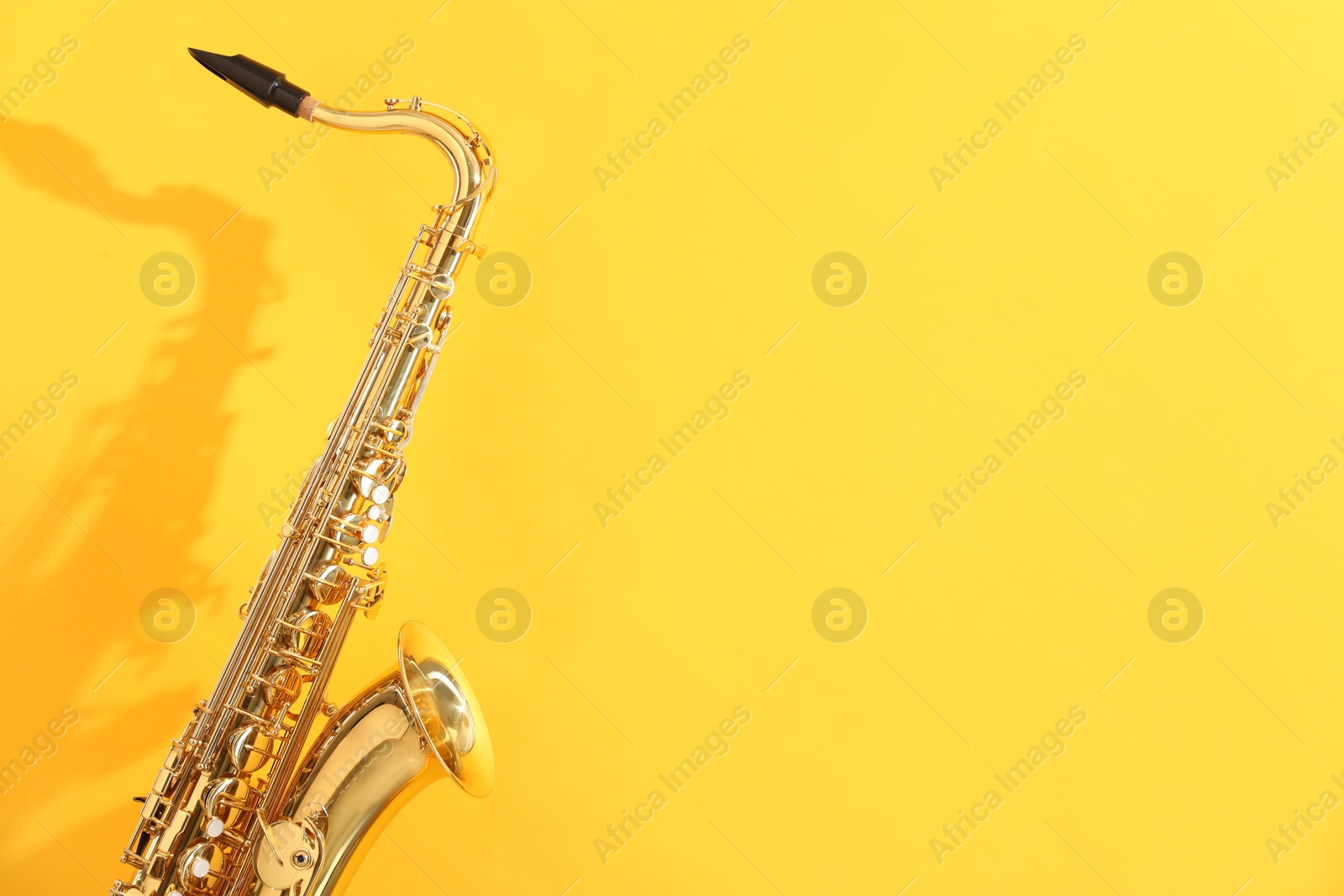 Photo of Golden saxophone on yellow background. Space for text