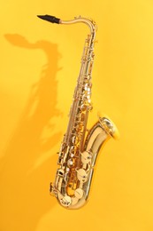 Photo of Golden saxophone on yellow background. Musical instrument