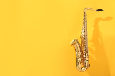 Photo of Golden saxophone on yellow background. Space for text