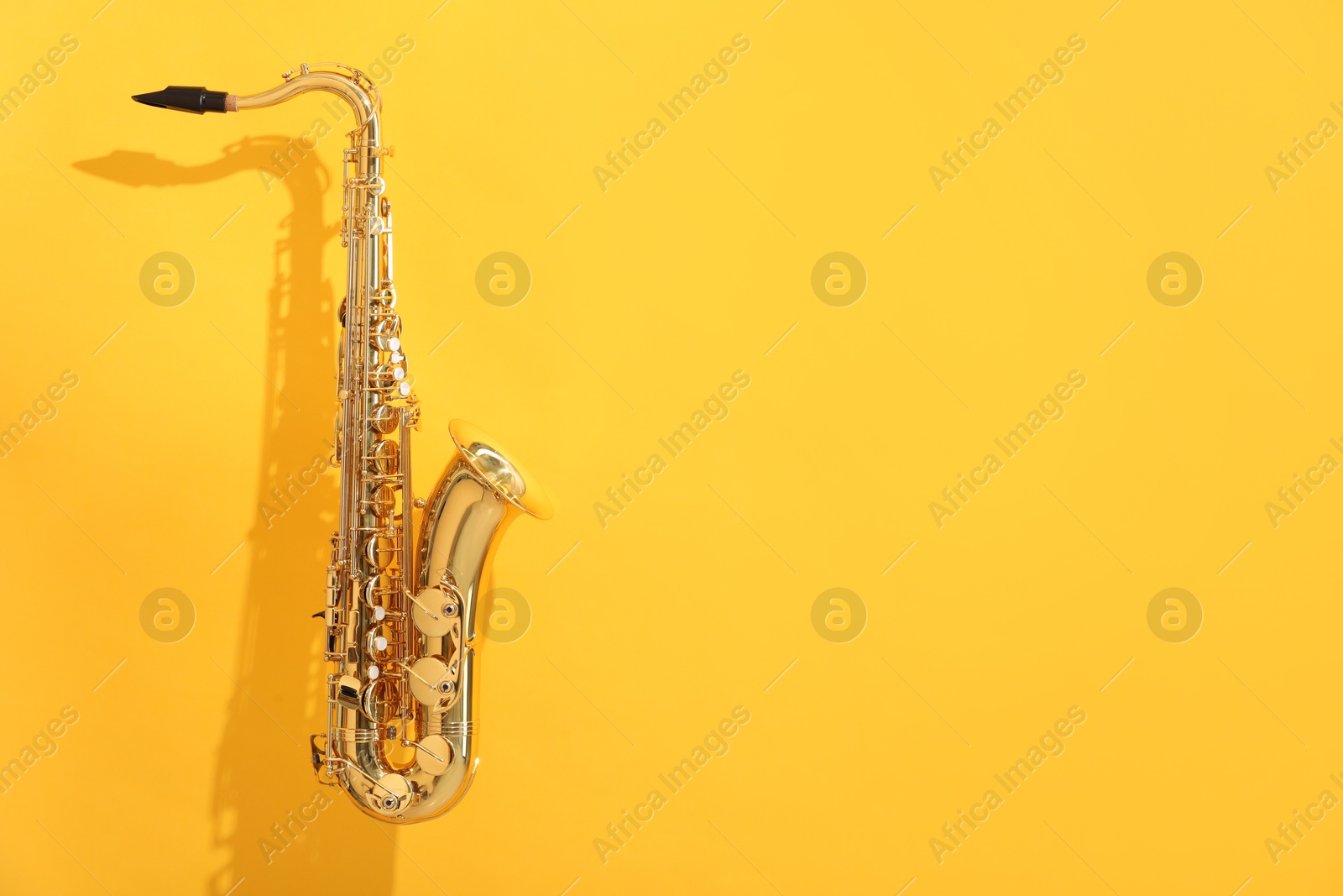 Photo of Golden saxophone on yellow background. Space for text