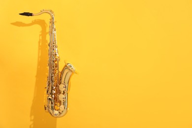 Photo of Golden saxophone on yellow background. Space for text