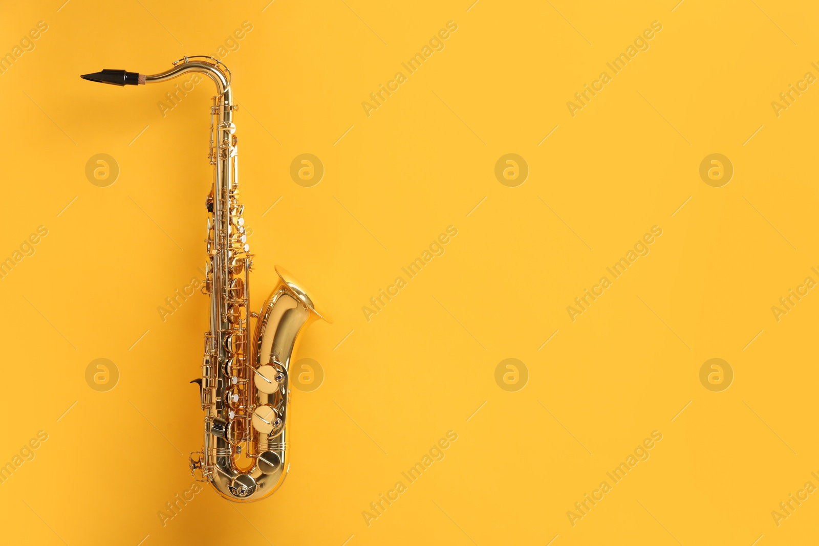 Photo of Golden saxophone on yellow background. Space for text