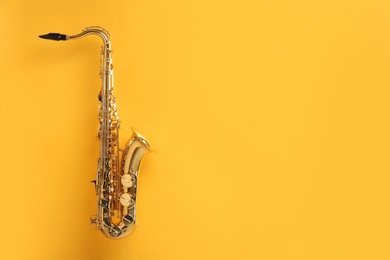 Photo of Golden saxophone on yellow background. Space for text