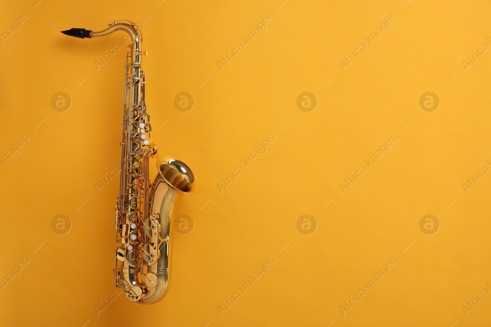 Photo of Golden saxophone on yellow background. Space for text