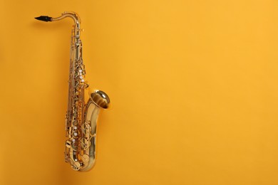 Photo of Golden saxophone on yellow background. Space for text