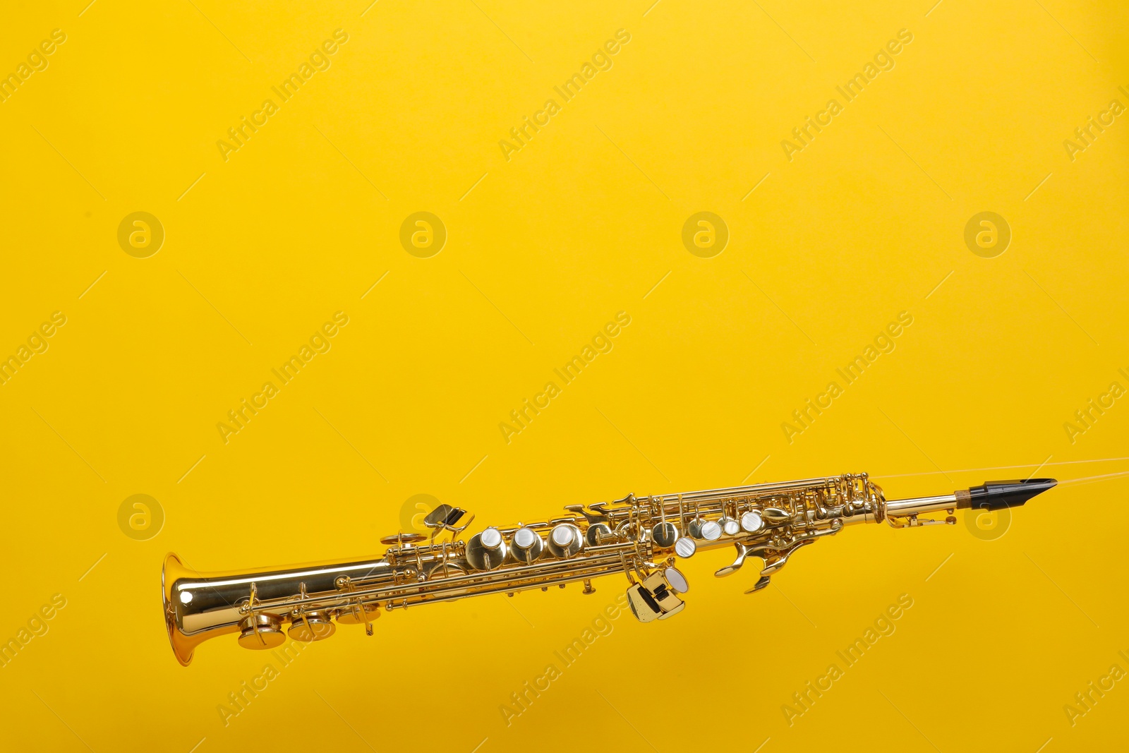 Photo of Golden soprano saxophone on yellow background. Space for text