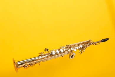 Photo of Golden soprano saxophone on yellow background. Space for text