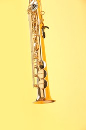 Photo of Golden soprano saxophone on yellow background, closeup