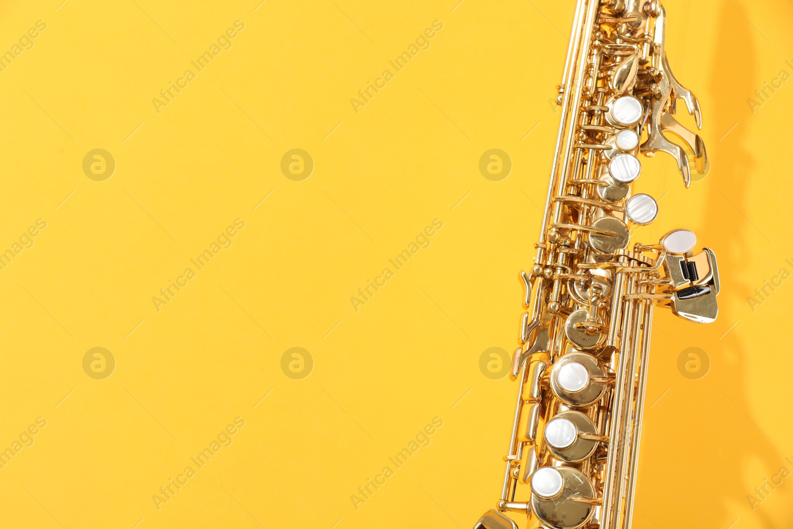 Photo of Golden soprano saxophone on yellow background, closeup. Space for text