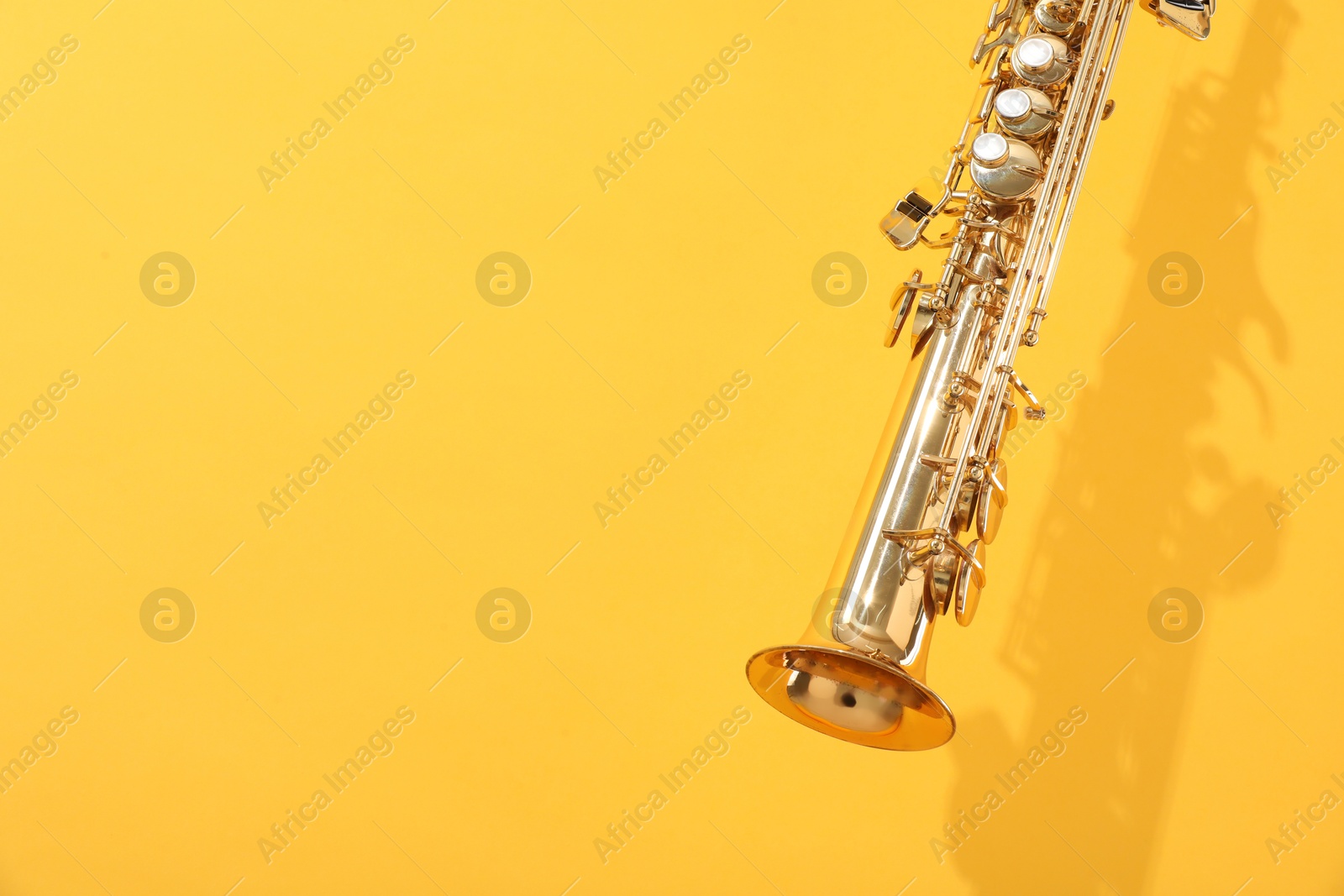 Photo of Golden soprano saxophone on yellow background, closeup. Space for text