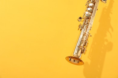 Photo of Golden soprano saxophone on yellow background, closeup. Space for text