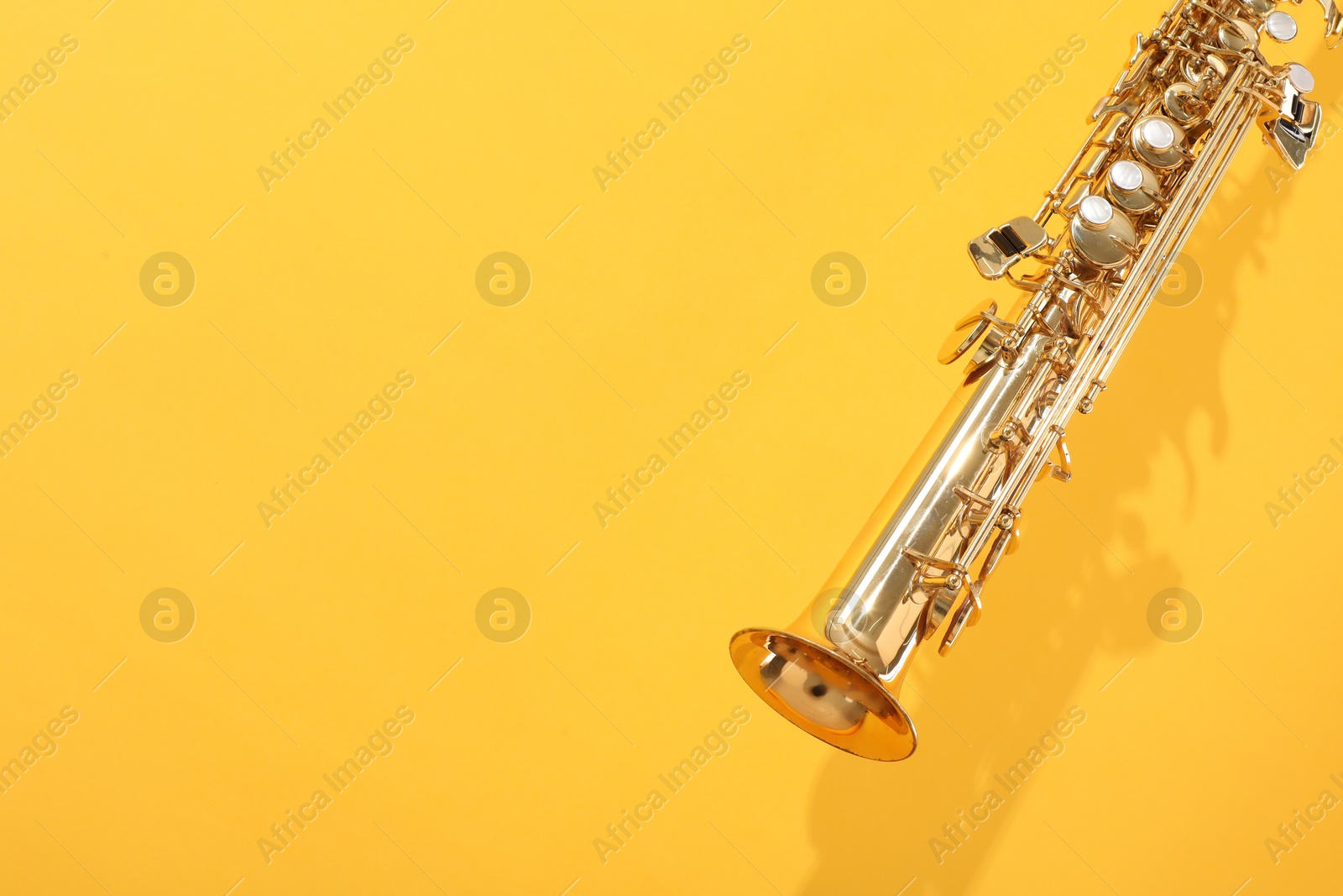 Photo of Golden soprano saxophone on yellow background, closeup. Space for text