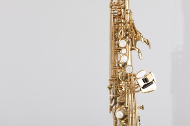 Photo of Golden soprano saxophone on light grey background, closeup. Space for text