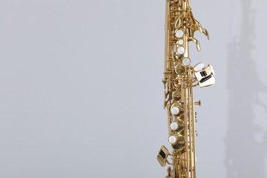 Photo of Golden soprano saxophone on light grey background, closeup. Space for text