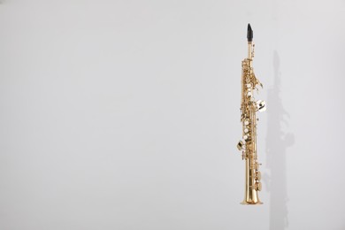 Photo of Golden soprano saxophone on light grey background. Space for text