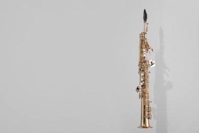 Photo of Golden soprano saxophone on light grey background. Space for text