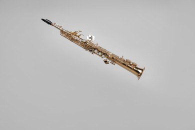 Photo of Golden soprano saxophone on light grey background. Space for text