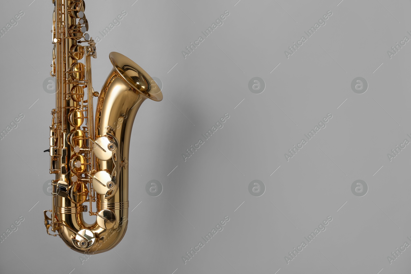 Photo of Golden saxophone on grey background. Space for text